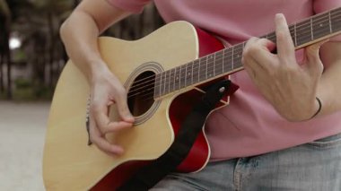 Sahilde çalan akustik gitarın yakın çekimi, dinamik tıngırtı ve parmak tekniklerini yakalıyor.