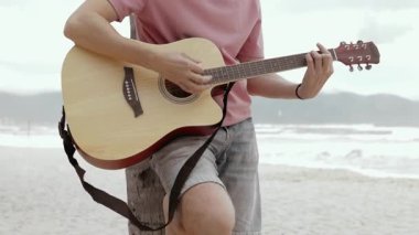 Okyanus dalgalarında tıngırdayan akustik plaj gitaristi