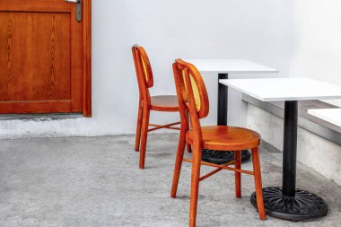 Ahşap sandalyeli ve beyaz masalı rahat bir kafeterya..