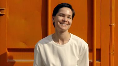 Parlak turuncu arka planda gülümseyen ve güneşli günün tadını çıkaran kadın