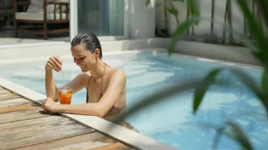 Sakin bir yaz inzivasında serinletici bir içecek havuzu başında rahatlamış bir kadın.