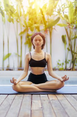 Meditasyon pozunda yoga yapan Asyalı genç bir kadın..