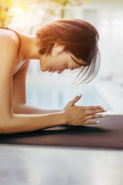 Genç Asyalı kadın havuz başında yoga tahtası pozu veriyor..