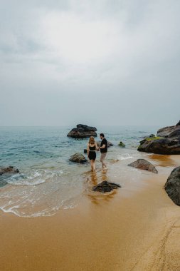 Kafkasyalı genç bir çift okyanus kıyısında sakin bir sahil yürüyüşü yapıyor..
