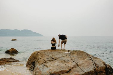 Bulutlu bir günde sakin bir plajın tadını çıkaran beyaz bir çift..