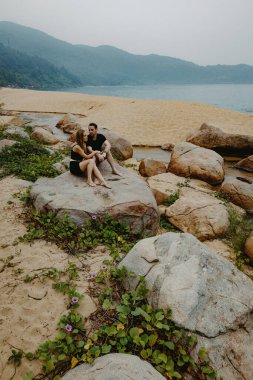 Kafkasyalı genç çift kayalık sahilde dinleniyor manzaralı kıyı manzaralı.