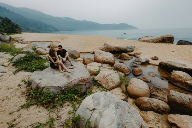 Kafkasyalı çift okyanus manzaralı kayalık sahil şeridinde dinleniyor..