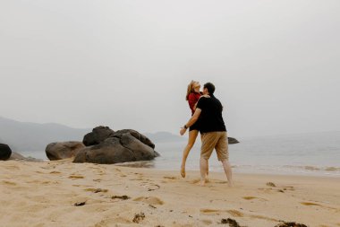 Neşeli çift bulutlu bir plaj gününün tadını çıkarıyor..