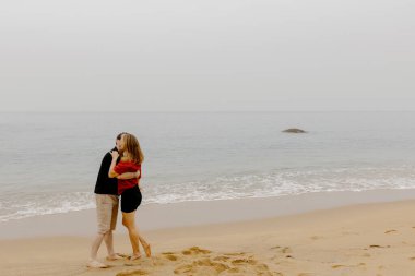 Kafkasyalı genç çift sisli ufkuyla sakin kumsalda kucaklaşıyorlar..