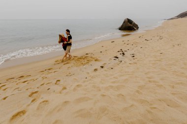 Genç, beyaz bir çift kumsalda yürüyüş yapıyor..