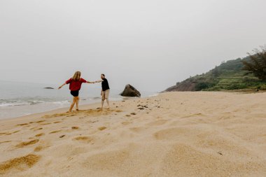 Kafkasyalı genç bir çift huzurlu kumsalda neşeyle geziniyor..