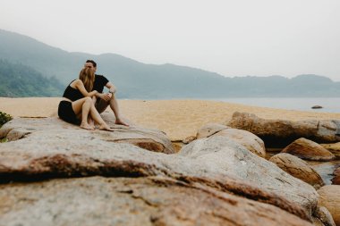 Kafkasyalı çift kayalık kıyı şeridinde sakin kumsal anlarının tadını çıkarıyor..