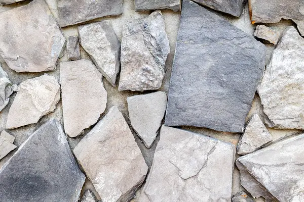 Düzensiz gri ve bej taşlı taştan duvar dokusu.