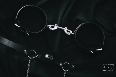 Siyah deri bdsm bağlar ve koyu kumaş arka planda top ağzı.