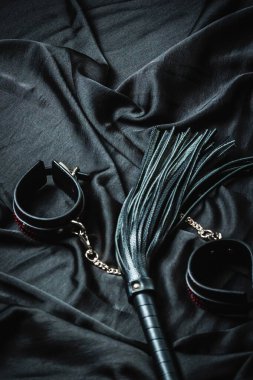 Koyu renk kumaş arka planında siyah deri bdsm aksesuarlar.