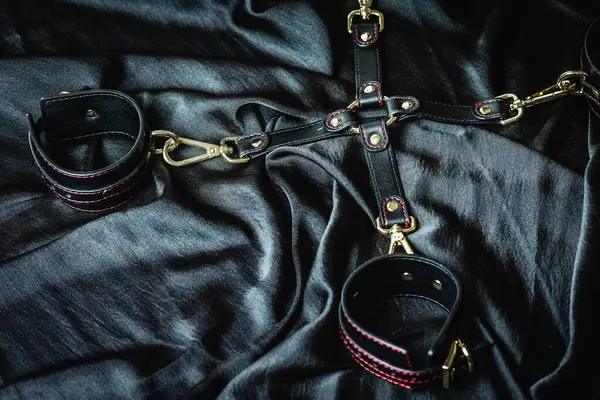 Siyah deri kayışlar ve ipek kumaş arka planda metal tokalar..