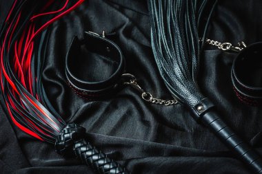 Koyu renk kumaşta kırmızı ve siyah deri bdsm aksesuarlar.