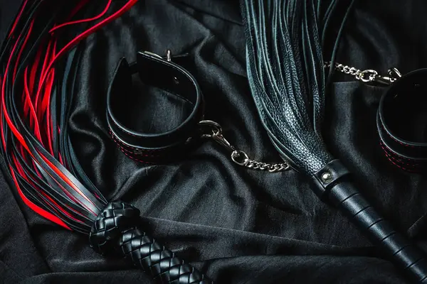 Koyu renk kumaşta kırmızı ve siyah deri bdsm aksesuarlar.