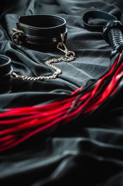 Koyu renk kumaş üzerine siyah ve kırmızı bdsm aksesuarlar.