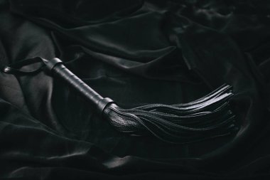 Koyu renk arkaplanda siyah deri kırbaç..