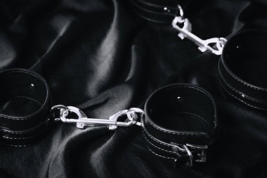 Siyah saten kumaş üzerine metal kelepçe. Detaylı ve yansımalı..