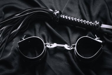 Siyah kumaşta deri kamçı ve kelepçe - bdsm araçları.
