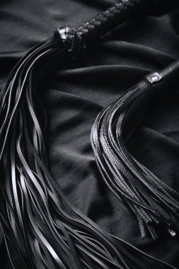Siyah deri kırbaçların siyah kumaşa yakın çekimi..