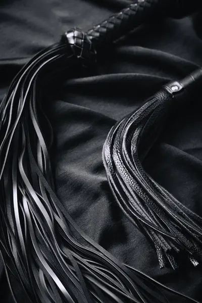 Siyah deri kırbaçların siyah kumaşa yakın çekimi..