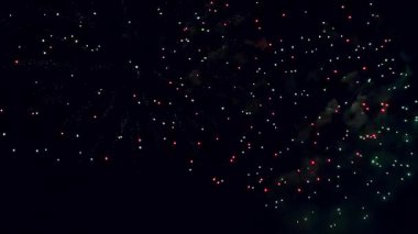 Gece gökyüzünde kırmızı ve yeşil patlamalarla patlayan canlı havai fişekler.
