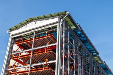 Çelik iskeleti ve mavi gökyüzüne karşı cam cepheli modern sanayi binası.