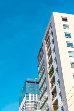 Şehir manzarasında mavi gökyüzüne karşı modern şehir mimarisi.