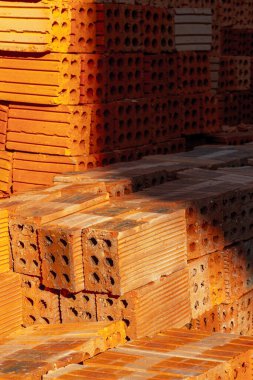 Güneşli inşaat alanında istiflenmiş kırmızı kil tuğlalar.