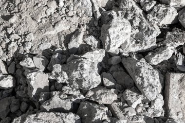 Güneş ışığı altında gri kaya ve moloz yığını.