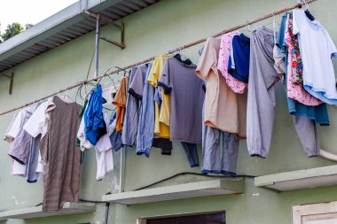 Dışarıdaki çamaşır ipinde yeşil duvara karşı kuruyan çeşitli giysiler..