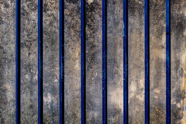 Dikey mavi çizgileri ve yıpranmış yüzeyi olan desenli beton duvar..