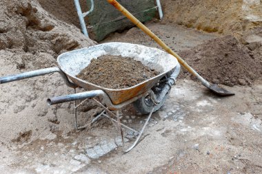 İnşaat alanında kum ve kir dolu paslı el arabası..