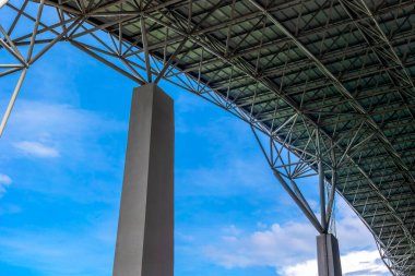 Mavi gökyüzüne karşı mimari yapı çelik kirişler ve beton sütunlar içerir.