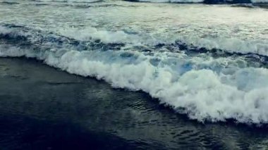 Dinamik okyanus dalgaları köpük desenleriyle kıyı şeridine çarpıyor.
