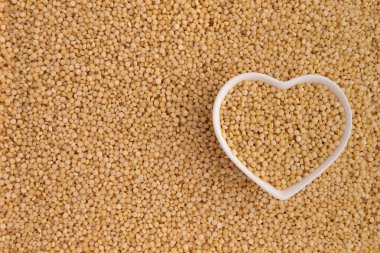 Kuru kuskus, sağlıklı kahvaltı konsepti, yemek malzemesi ve üst görünümün arka planında kalp şeklinde seramik kase.