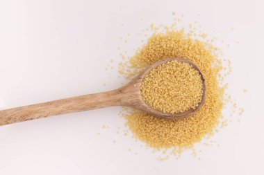 Tahta kaşıkta kuru kuskus. Beyaz arka planda izole edilmiş. Üst manzara.