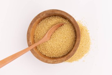 Tahta kasede kuru kuskus ve beyaz arka planda izole kaşık.