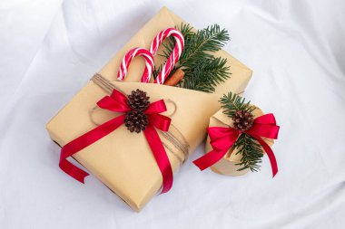Noel, yeni yıl hediyeleri. Hediyeler. Güzel kutular, kurdeleler ve dekorasyonlar. Beyaz arka planda ağaç konileri. Kırmızı. El işi kağıdı. Tatil günü. Orijinal. Tarçın. Şeker. Paket Tasarımı