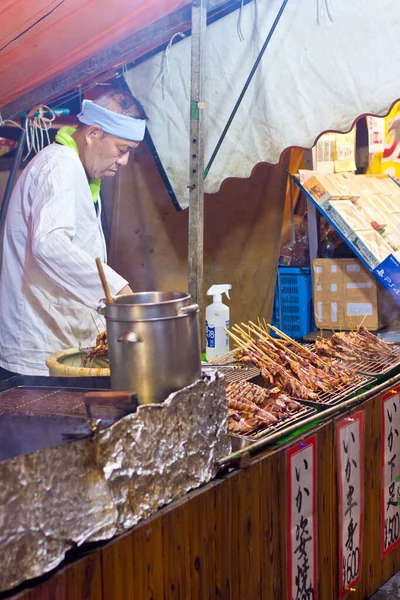 Japonya 'da bir matsuri sırasında geleneksel bir pazarda Asyalı bir adam.