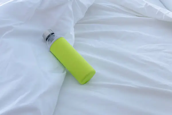 stock image Stylish Glass Water Bottle with Colorful Sleeve on White Bed Linens