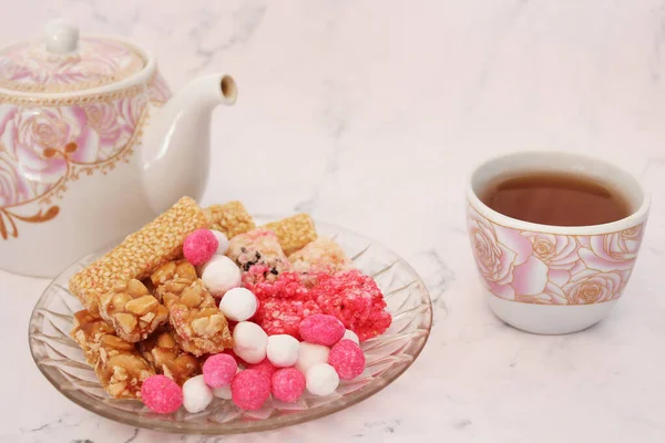 Hot tea cup with Chinese sweetmeat made of many ingredients (called Kanom Chan ap in Thai), on white background.