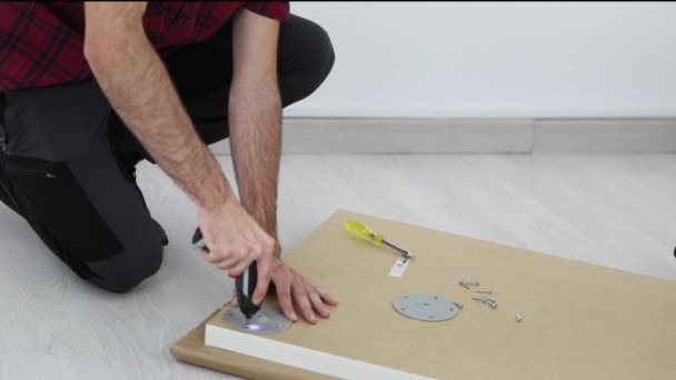 一个穿着黑色裤子和红色格子衬衫的木匠 把写字台的腿组装在一起 Uhd — 图库视频影像