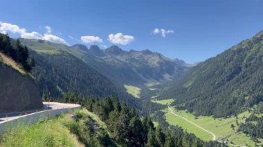 İspanya 'nın Baqueira şehrinde yaz mevsimi, muhteşem vadi manzaralı virajlı dolambaçlı bir dağ yolunda motosikletlilerle geçiyor..