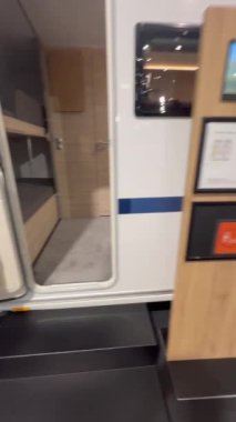 Koltukları, masası, yatakları ve pencereleri olan, rahat ve işlevsel bir alanı olan modern bir karavanın iç görünümü.