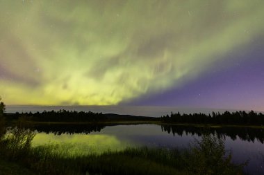 İsveç 'in Kiruna kentindeki kuzey ışıkları Eylül ayında sakin suları yıldızlar ve ormanlarla yansıtıyor..