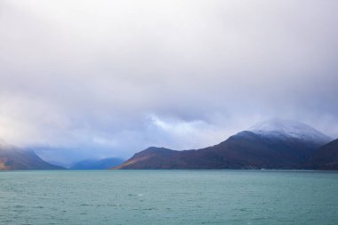 Norveç 'teki Lyngen Alpleri' nin sonbahar manzarası. Karlı zirveleri, dramatik bulutları ve sakin fiyortları var..